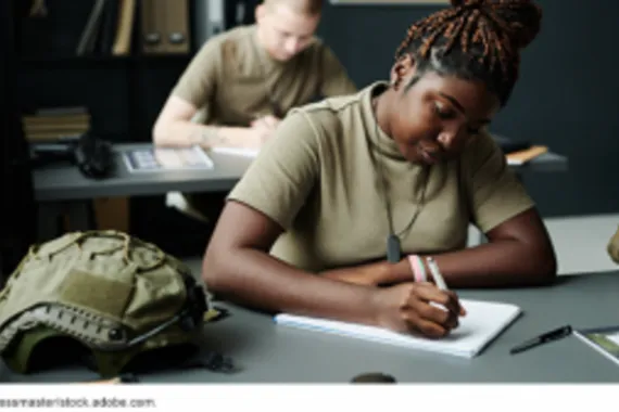 Military personnel writing at desks.