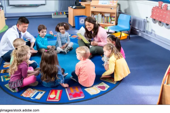 Children and teachers in a daycare sitting in a circle on the floor.