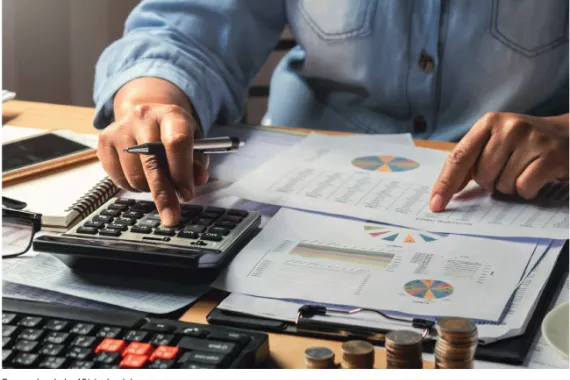 This shows a person using a calculator and reviewing paper reports.