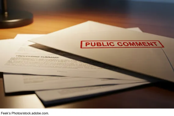 An envelope labeled 'public comment' lays on top of several pages of paper.