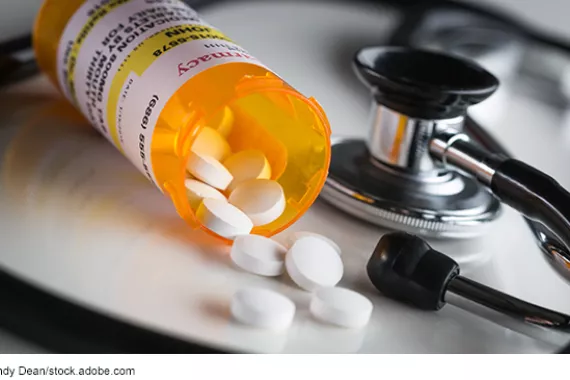 Non-proprietary prescription medication bottle and spilled pills with a stethoscope.