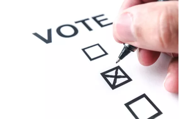 A person places an x inside a square to cast a vote.