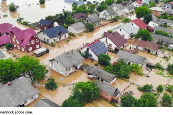 Aerial image showing a flooded residential neighborhood with homes and gardens submerged.  