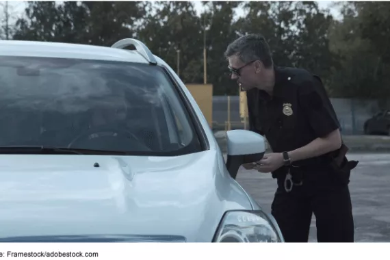 Police officer speaking to a driver of a vehicle through the open driver side window. 