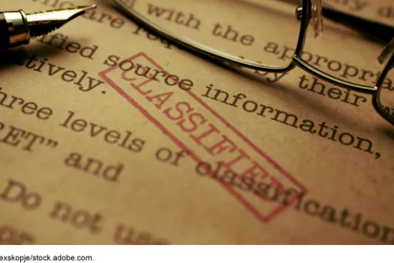 Pen over a paper stamped classified. 