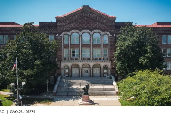 The front of a brick school building with a stairway leading up to the entrance.
