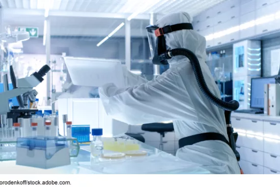 A person wears protective gear while working in a biological research lab. 
