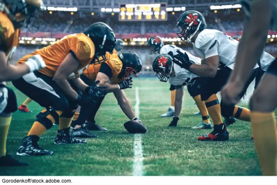 Football teams face each other in the middle of a football field.