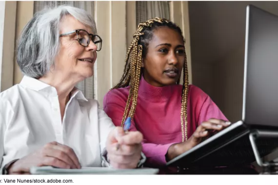 A picture of two people indoors looking at computer.