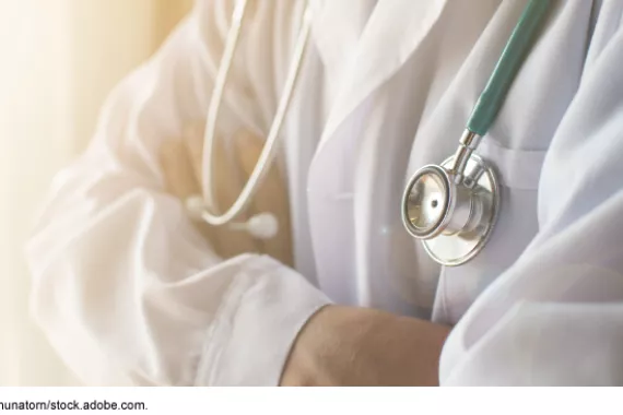 Person in white coat with stethoscope around their neck.