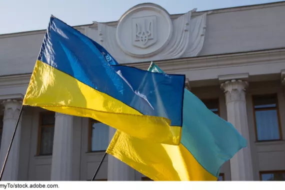 Two Ukrainian flags fly in front of the Ukrainian parliament building.