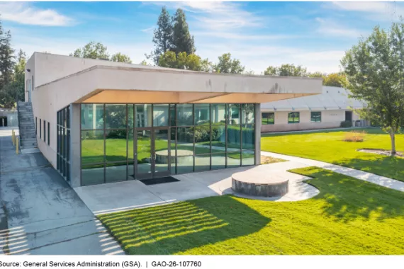 An office building with a large glass wall and a lawn. 