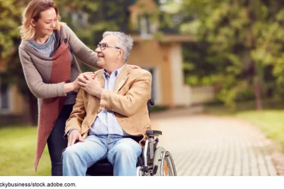 A woman interacts with a man in a wheelchair.