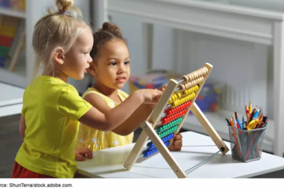 Two young children use an abacus in a preschool classroom.
