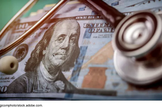 A stack of 100-dollar bills with a stethoscope on top.