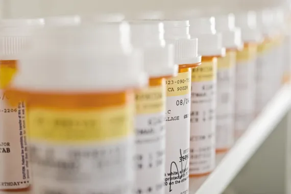 Prescription drug bottles in a line on a shelf