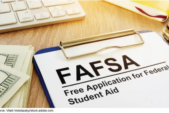 Free Application for Federal Student Aid on a desk with computer keyboard and money for college.