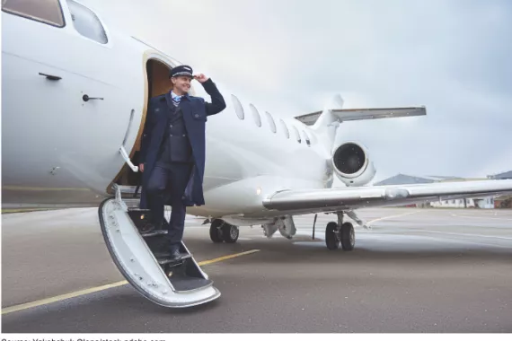A small regional airplane on the tarmac with a pilot standing on steps leading to the open door for boarding.