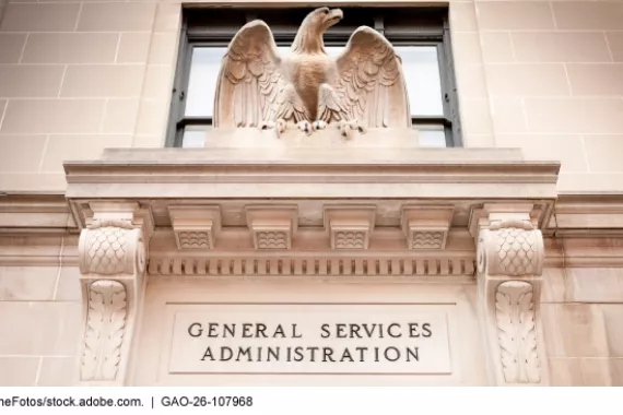 A light-colored stone building facade with a sculpture of an eagle above the words General Services Administration 