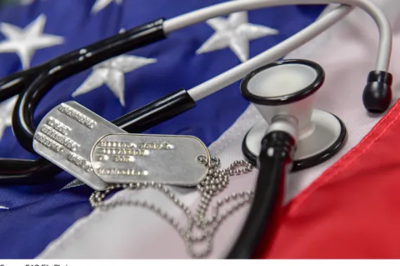 Picture of a stethoscope and military identification tags placed on top of an American flag.