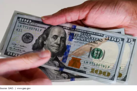 Photo of two people exchanging $100 bills