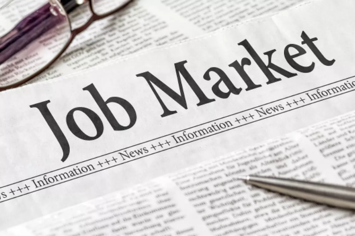 Newspaper-style document with the banner "Job Market" written on top and a pen laying across it.