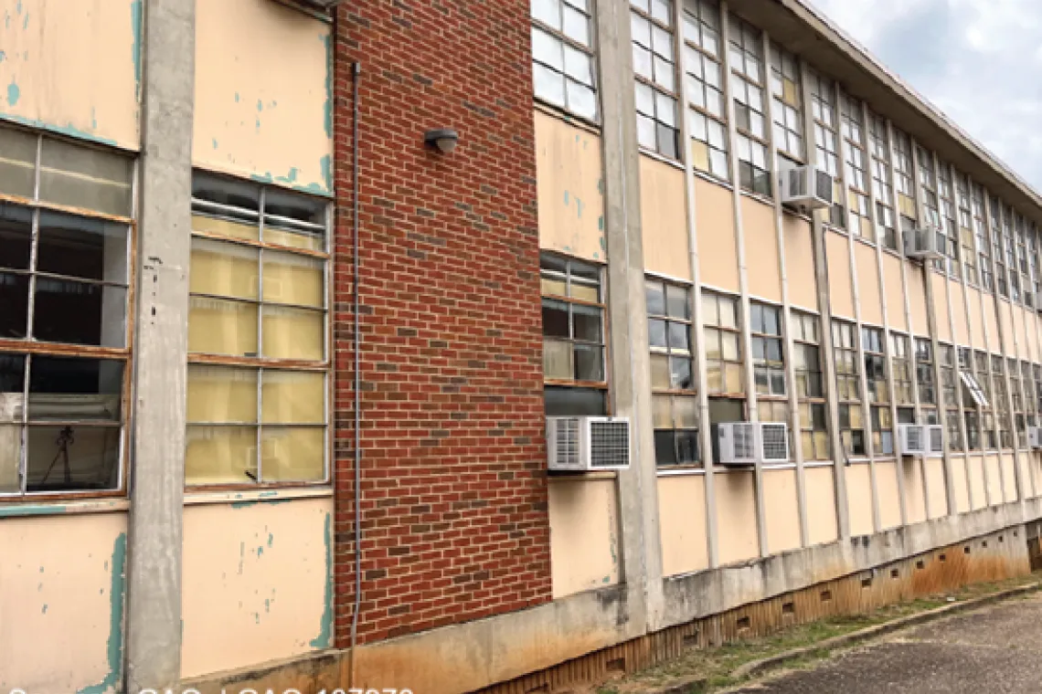 A photo of a school with broken windows and wall air conditioning units.