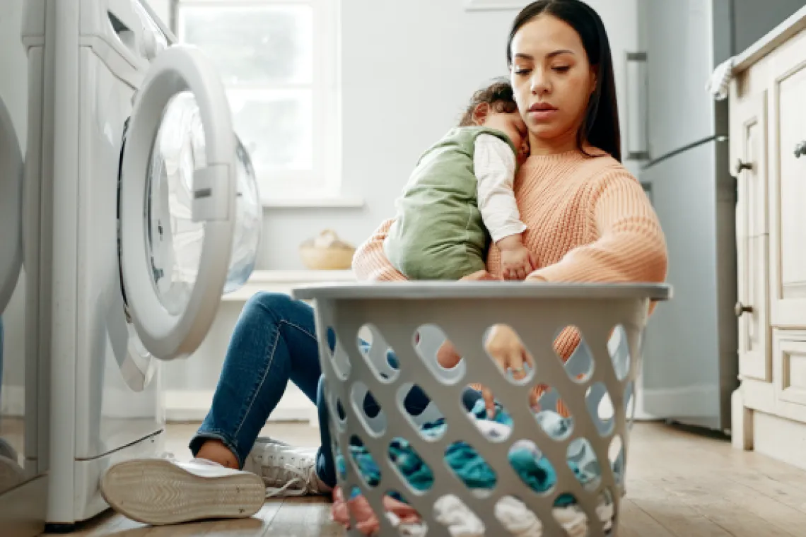 A woman doing laundry while holding a child.
